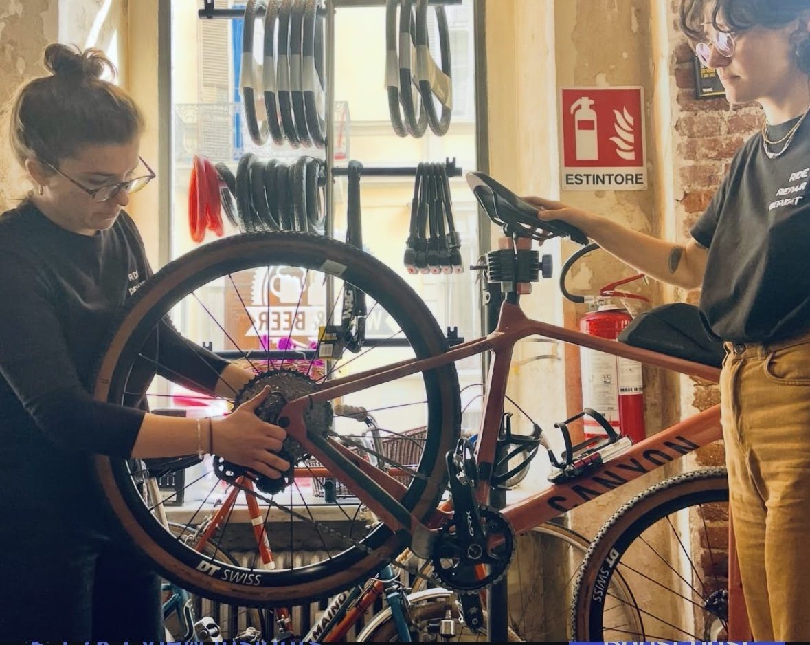 Two women working together on a bicycle mounted in a repair stand